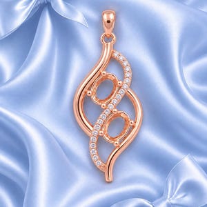 Peut inclure: Un pendentif en or rose présentant deux sertis ovales vides pour pierres précieuses, disposés dans un design allongé et tourbillonnant. Un côté de la monture en métal est orné d'une rangée de petites pierres rondes transparentes.