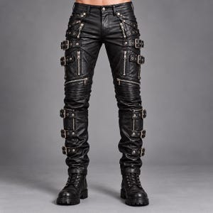 Könnte beinhalten: Schwarze Hose mit lederartiger Oberfläche, mehreren silberfarbenen Metallreißverschlüssen und verstellbaren Schnallenriemen an den Beinen. Das Design umfasst gerippte Einsätze über den Knien sowie einen Knopfverschluss an der Taille.