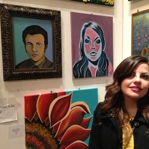 May include: A gallery wall display featuring three paintings: a portrait of a man in a dark ornate frame, a stylized portrait of a person with pink skin tones, and a large close-up painting of a sunflower with red and orange petals on a teal background.