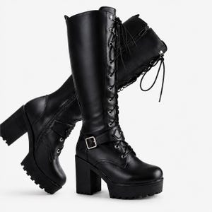 May include: A pair of black knee-high boots featuring a thick block heel, a chunky lug sole, and a lace-up front with silver-toned eyelets. Each boot includes a side zip closure and an adjustable ankle strap with a silver-toned metal buckle.