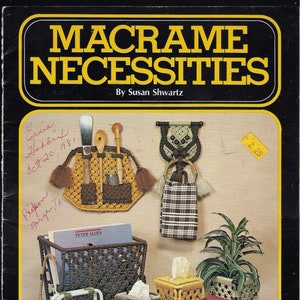 May include: A book cover with the title "Macrame Necessities" by Susan Shwartz. The cover features a variety of macrame projects, including a wall hanging, a tissue box cover, and a mirror. The book also includes the text "23 Clever Projects For Every Room of Your House. Mirrors, Clocks and Jewelry Racks... and Much More. #7421"