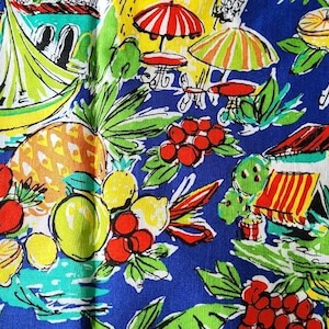 May include: A vibrant blue fabric featuring a tropical design. The pattern includes sailboats, pineapples, lemons, and red berries. Small tables with umbrellas and buildings with red and white striped awnings are also depicted. The overall theme is a colorful, summery scene.