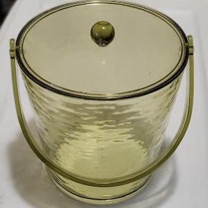 May include: A clear green plastic ice bucket with a lid and two handles. The bucket has a textured surface.