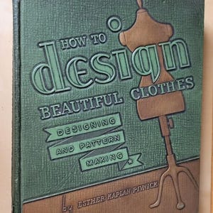 May include: A green and brown hardcover book titled How to Design Beautiful Clothes: Designing and Pattern Making by Esther Kaplan Pivnick. The cover features an embossed illustration of a dressmaker's mannequin on a tripod stand.