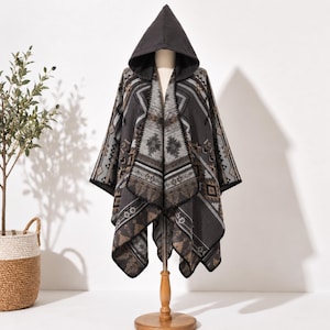 May include: A hooded poncho featuring a dark gray, light gray, and brown geometric pattern. The garment has an open front design with a black stitched border along the edges and a pointed hood. The fabric displays a repeating symmetrical motif.