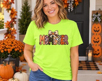 Könnte beinhalten: Ein neongrünes Kurzarm-T-Shirt mit dem Wort MOMSTER in bunten, gemusterten Blockbuchstaben und einer Schleifengrafik darüber. Die Buchstaben zeigen Designs wie orangefarbenes Karomuster, lila mit Geistern, orange Streifen und Kürbisse.