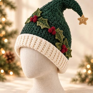 May include: A dark green crocheted hat with a cream-colored ribbed brim. The hat features a pointed top adorned with a small gold crocheted star and a decorative band of green crocheted holly leaves paired with clusters of small red berries.