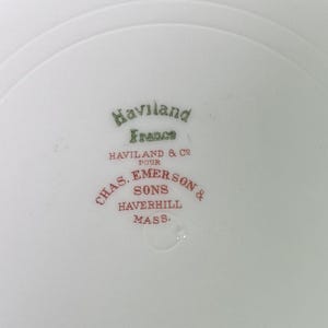May include: Close-up of a white porcelain plate with the text "Haviland France" in green and "CHAS. EMERSON & SONS HAVERHILL MASS." in red. The plate has a subtle, curved rim.