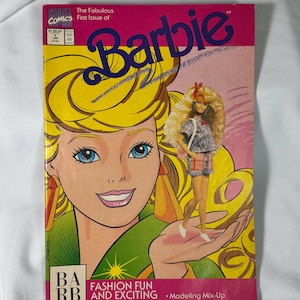 May include: A vintage Barbie comic book cover with a cartoon Barbie with blonde hair and blue eyes. The cover is pink and yellow with the title "Barbie" in large letters. The comic book is titled "The Fabulous First Issue of Barbie" and includes the text "Fashion Fun and Exciting Escapades!"