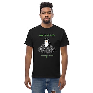 Könnte beinhalten: Ein schwarzes Kurzarm-T-Shirt mit einer Grafik eines traurigen Pinguins, der auf einem Haufen Computerhardware sitzt. Der Text "sudo rm -rf /life" steht oben und "Permission denied... still here" unten in leuchtend grüner Schrift.