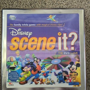 Può includere: Una scatola di metallo quadrata per il gioco in DVD Disney Scene It?. La copertina viola presenta vari personaggi Disney e Pixar, un grafico a disco DVD colorato e il testo: The family trivia game with magical Disney clips! Featuring Your Favorite Disney Pixar Characters!