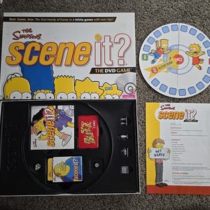 Può includere: Il gioco da tavolo in DVD The Simpsons Scene It? include una scatola rettangolare con grafiche dei personaggi, un tabellone circolare con Bart e Lisa, un vassoio da gioco in plastica nera con carte e gettoni e un manuale di istruzioni.