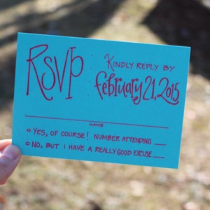 Puede incluir: Una tarjeta RSVP turquesa con un RSVP escrito a mano en rojo y una fecha escrita a mano en rojo del 21 de febrero de 2015. La tarjeta tiene una l&iacute;nea para un nombre y dos opciones para responder: "&iexcl;S&Iacute;, POR SUPUESTO!" y "NO, PERO TENGO UNA MUY BUENA EXCUSA."