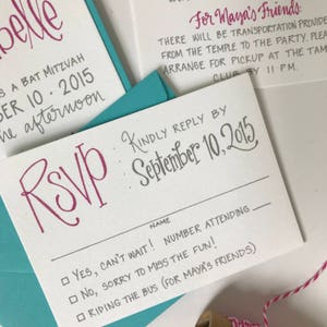 Puede incluir: Una tarjeta RSVP blanca con un RSVP rosa escrito en cursiva. La tarjeta tiene un encabezado gris que dice "Kindly Reply By September 10, 2015". Debajo del encabezado hay un espacio para un nombre y el n&uacute;mero de personas que asisten. Hay tres opciones para elegir: "Yes, can't wait!", "No, sorry to miss the fun!" y "Riding the bus (for Maya's friends)".