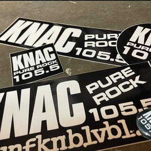 May include: A collection of black and white stickers and a button featuring the text "KNAC Pure Rock 105.5". The stickers are rectangular and oval, with the radio station's name and frequency prominently displayed.