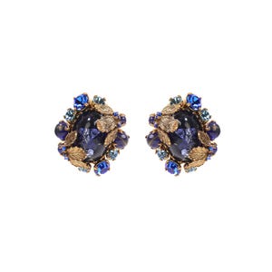 May include: A pair of ornate earrings featuring a large, dark blue central stone surrounded by smaller blue crystals and textured gold-tone metal leaves. The design incorporates a cluster of round blue beads and faceted stones set in a metallic frame.