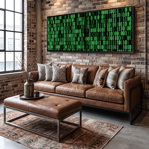May include: A rectangular wall art piece featuring a digital display of green binary code on a black background, framed in black. The artwork is mounted on a brick wall above a brown leather sofa with several patterned throw pillows and an ottoman.