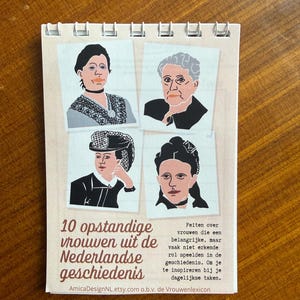 May include: A spiral-bound notepad featuring illustrations of four women. The notepad's cover includes the text "10 opstandige vrouwen uit de Nederlandse geschiedenis" and additional text in Dutch. The illustrations are in a simple, colorful style.