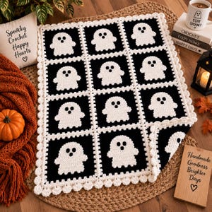 May include: A rectangular crochet blanket featuring a repeating pattern of white ghost motifs on black square panels. The blanket is bordered with a scalloped white crochet edge. Each ghost has two circular black eyes and a circular black mouth.