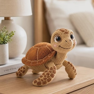 Op de afbeelding: Een gehaakt schildpad knuffeltje met een lichtbruine kop en ledematen met donkerbruine vlekken, een gestructureerd bruin schild, grote donkere ogen en kleine roze geborduurde wangen. De schildpad staat in een houding met een glimlach.