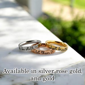 May include: Three thin stacking rings with engraved messages: "+ be still", "let them", and "Just breathe". Available in silver, rose gold, and gold.