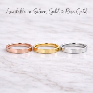 Może przedstawiać: Trzy pierścionki w kolorze r&oacute;żowego złota, złota i srebra, prezentowane na marmurowej powierzchni. Pierścionki to proste obrączki o płaskim designie. Tekst u g&oacute;ry brzmi "Available in Silver, Gold & Rose Gold."