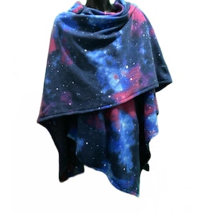 May include: A navy blue fleece poncho with a galaxy print featuring shades of blue, pink, and white. The poncho has a cowl neck and a triangular shape.