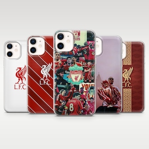 May include: Five clear smartphone cases featuring Liverpool Football Club designs. Designs include the red LFC crest, diagonal red stripes, a collage of players and the club logo, a player holding a trophy, and a gold crest with a geometric border.