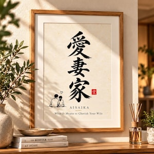 Puede incluir: Una lámina enmarcada con grandes caracteres de caligrafía japonesa en negro dispuestos verticalmente. Debajo del texto hay una pequeña ilustración de dos personas sentadas juntas con un corazón, la palabra AISAIKA y el texto What It Means to Cherish Your Wife.