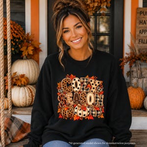 Op de afbeelding: Een zwart sweatshirt met lange mouwen en een grafische print met de tekst COZY SEASON in een mix van luipaard-, stippen- en ruitpatronen, vergezeld van drie geïllustreerde pompoenen en herfstbladeren.