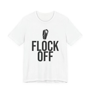 Könnte beinhalten: Ein weißes T-Shirt mit kurzen Ärmeln, das eine schwarze Grafik einer Vogelsilhouette über dem Text FLOCK OFF in fetten, schwarzen, serifenlosen Großbuchstaben mittig auf der Brust zeigt, mit einem Rundhalsausschnitt und einem geraden Saum.