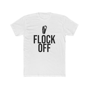 Puede incluir: Una camiseta blanca de manga corta con un gráfico negro de la silueta de un pájaro sobre el texto FLOCK OFF impreso en letras mayúsculas negras y negritas en el centro del pecho. La prenda tiene cuello redondo y un dobladillo recto.