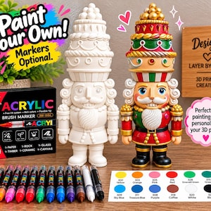 May include: Two nutcracker figurines, one plain white and one painted in red, green, and gold, accompanied by a 12-pack of acrylic brush markers and a color reference chart. The box text reads Paint Your Own! Markers Optional and Acrylic.