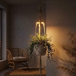 May include: A hanging macrame plant holder in a natural beige cord featuring an integrated circular LED light ring above a white ceramic pot containing a lush green trailing plant, suspended from a cord with a decorative tassel at the base.