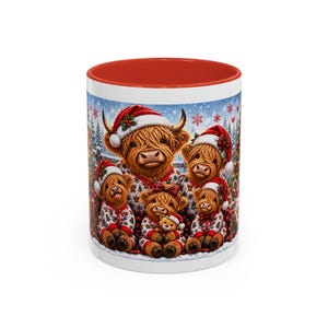 Op de afbeelding: Een witte keramische mok met een rode binnenkant en rand, voorzien van een kleurrijke illustratie van een familie van vijf Highland-koeien met rood-witte kerstmutsen en bijpassende pyjama's tegen een achtergrond van een besneeuwd bos.