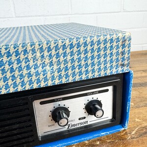 May include: Vintage Emerson radio with a blue and white houndstooth patterned top. The radio has a black face with silver controls for tone and volume. The brand name "Emerson" is printed on the face.