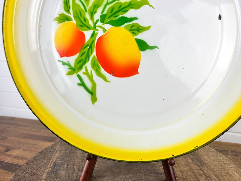 Puede incluir: Bandeja de servir de esmalte blanco con borde amarillo y un dise&ntilde;o pintado de hojas verdes y frutas naranjas.