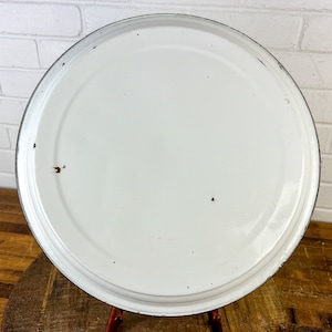 Puede incluir: Plato para tartas de esmalte blanco con borde negro. El plato tiene algunas marcas de desgaste.
