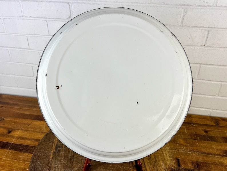 Puede incluir: Plato para tartas de esmalte blanco con borde negro. El plato tiene algunas marcas de desgaste.