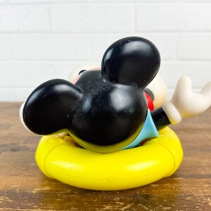 Puede incluir: Figura vintage de Mickey Mouse en un flotador amarillo. El personaje de orejas negras lleva una camisa azul y pantalones cortos rojos. Un objeto de colecci&oacute;n cl&aacute;sico de Disney.