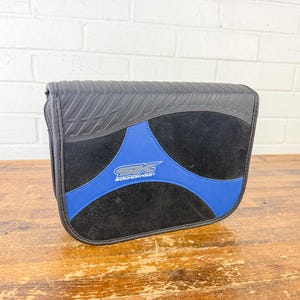 May include: Black and blue Soundcase carrying case. The case has a black rubberized top, a black suede-like center, and blue accents. The Soundcase logo is in the center of the blue accent.