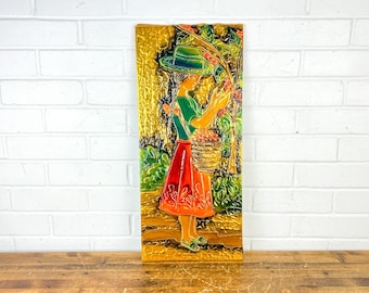 May include: A colorful relief sculpture depicting a figure in a green hat and shirt, and a red skirt, harvesting fruit. The figure holds a basket and reaches for the fruit. The background is a mix of gold, green, and brown tones.