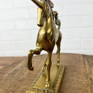 Puede incluir: Una figurita de unicornio de lat&oacute;n dorado con un cuerno y pezu&ntilde;as detalladas. El unicornio est&aacute; de pie sobre una base rectangular con un dise&ntilde;o ornamentado.