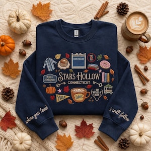 Könnte beinhalten: Ein marineblaues Sweatshirt mit Rundhalsausschnitt und einem Grafikdruck von Stars Hollow, Connecticut, mit Symbolen wie einer Kaffeetasse, Büchern und einem Pavillon. Die Ärmel sind mit dem Text where you lead und i will follow bestickt.