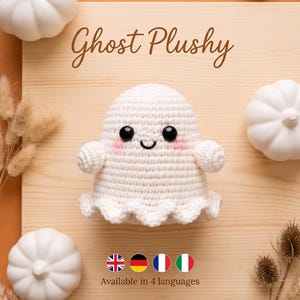 Op de afbeelding: Een witte gehaakte spookknuffel met zwarte veiligheidsoogjes, een geborduurde glimlach en roze blosjes op de wangen. De tekst Ghost Plushy staat boven de figuur en de tekst Available in 4 languages staat eronder.