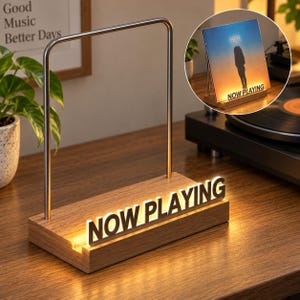 May include: A wooden vinyl record display stand featuring a metal arch and an illuminated sign that reads NOW PLAYING in bold letters. The base is crafted from wood with a slot for holding a record sleeve, providing a glowing display for music.