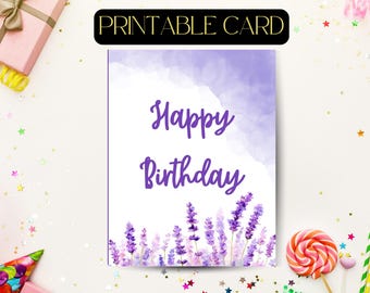 May include: A rectangular printable card featuring a watercolour-style purple wash at the top and a border of lavender sprigs at the bottom. The text "Happy Birthday" is written in a purple script font in the centre of the white card surface.