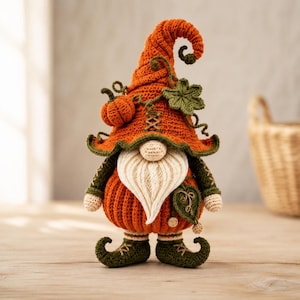 Peut inclure: Une figurine de gnome au crochet avec un grand chapeau orange pointu orné d'une petite citrouille et d'une feuille verte. Le gnome possède une barbe crème, un nez rond et un corps orange côtelé. Il porte des chaussures et gants vert foncé.
