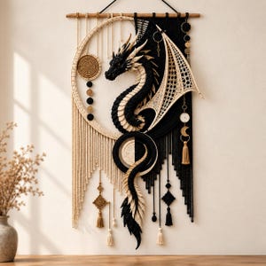 Può includere: Un grande arazzo da parete in macramè con un design centrale a forma di drago in nero e crema. L'opera è appesa a un bastone di legno e incorpora cornici circolari, nodi complessi, nappe pendenti e accenti geometrici bicolore.