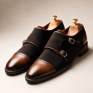 Pode incluir: Um par de sapatos de fivela dupla em camurça e couro castanho escuro, com biqueira polida com detalhes brogue, duas fivelas prateadas e formas de madeira clara inseridas na zona do calcanhar de cada sapato.